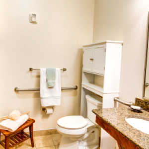 bathroom in community apartment with toilet, sink and towels