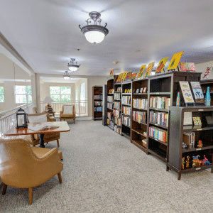 room with book shelves filled with books and comfortable chairs to read in