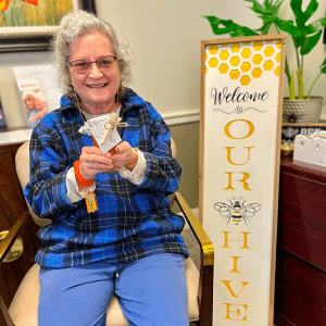 Elderly woman smiling and holding up a piece of art