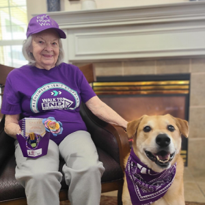 A sweet elderly lady in purple sitting next to her furry friend, a cute dog.