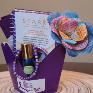 A lovely gift basket filled with sparkly surprises, including a beautiful purple flower and an intriguing book.