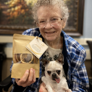elderly woman holding a dog and dog treats