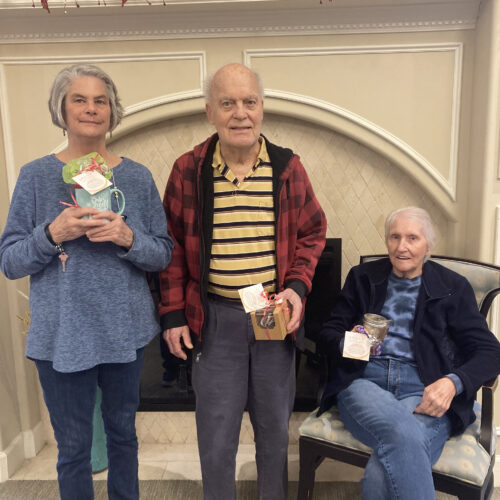 Three elderly people smiling holding their crafts