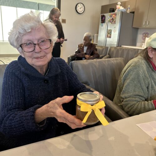 Picture of an old lady holding a jar of homemade jam.
