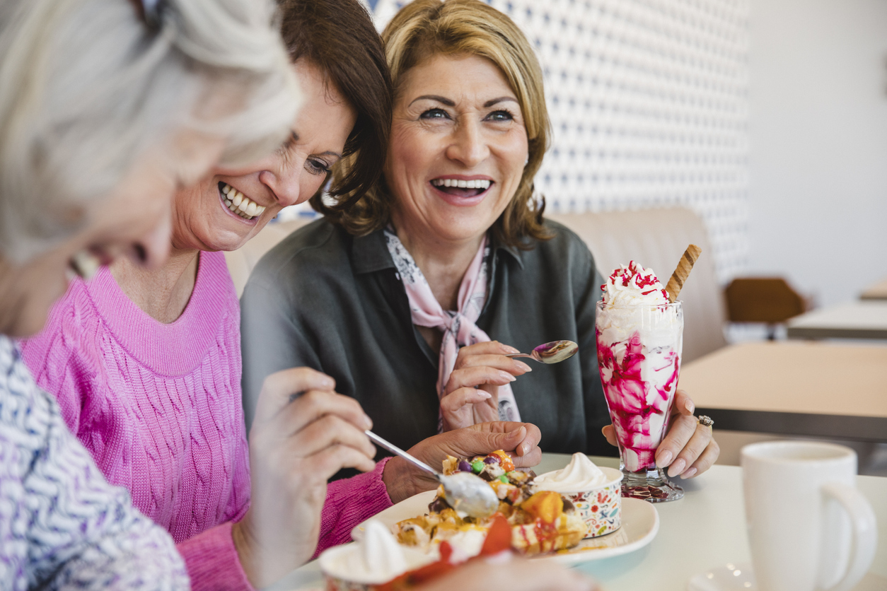 Cheerful senior women laughing together in ice cream parlour