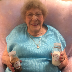 elderly woman holding 2 jars of sugar scrub