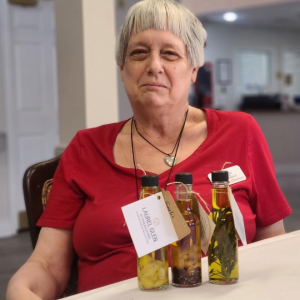 elderly woman with jar of herbs in oil