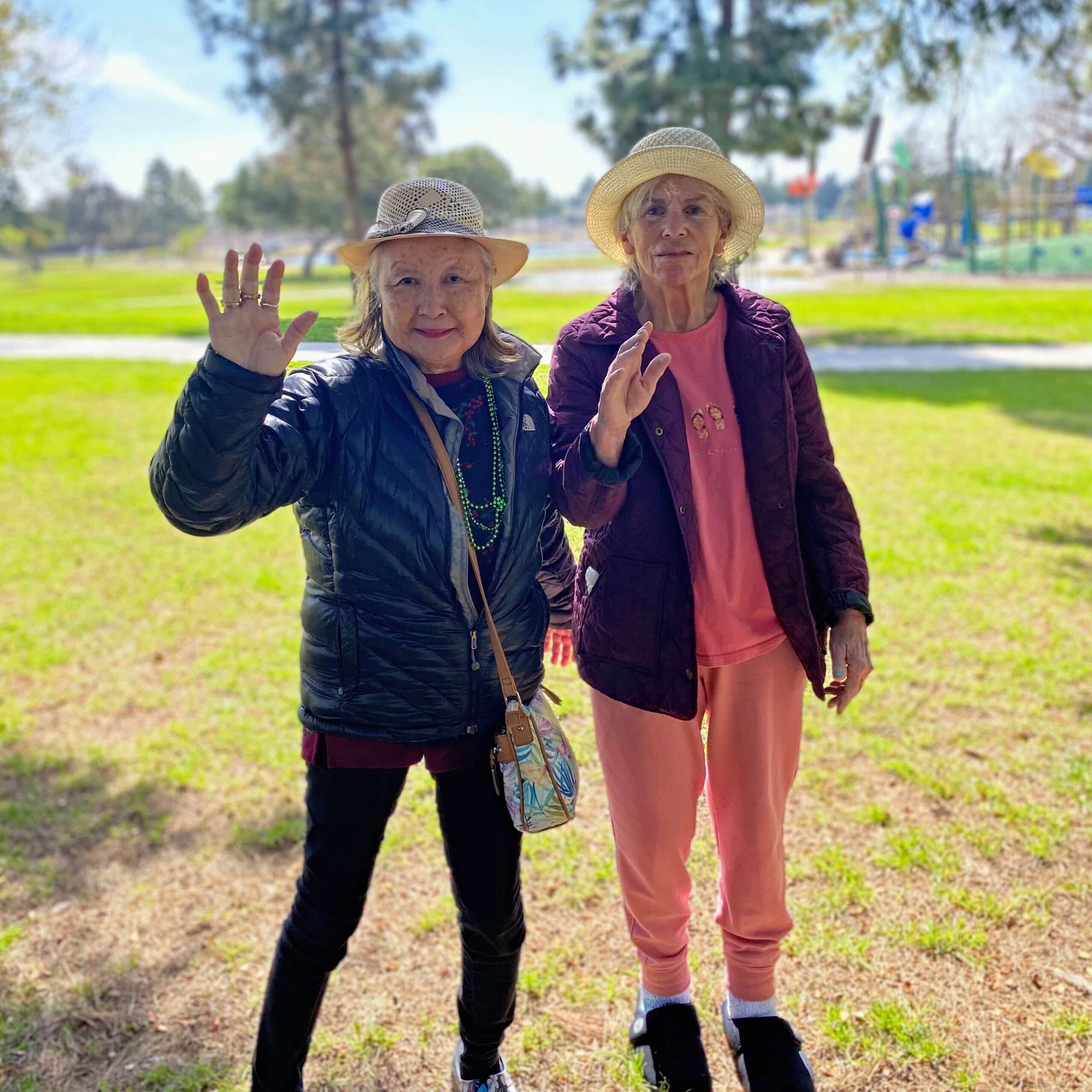 Two elderly women hanging out in a park surrounded by green grass