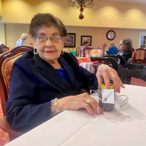 Elderly woman enjoying coffee at a table.