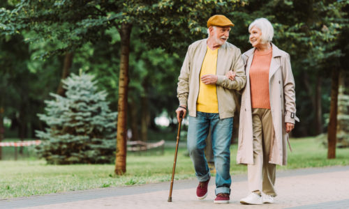Senior couple smiling while walking on path in park