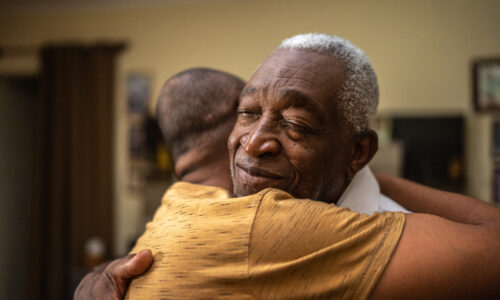 two elderly men embracing and hugging each other