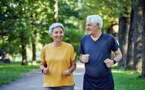 Senior couple jogging in the summer park Mature smiling grey-haired fit couple jogging in the summer park. Two older joggers enjoy morning active cardio outdoors, keep healthy active lifestyle. Weightloss, sport concept excercise senior stock pictures, royalty-free photos & images