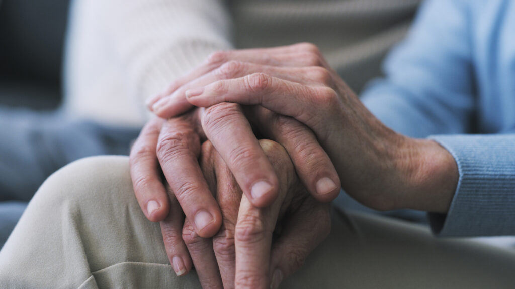 two elderly people holding hands