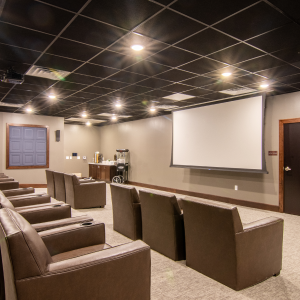 Get ready for a cozy movie night in a theater room filled with comfy leather chairs and a big projector screen.