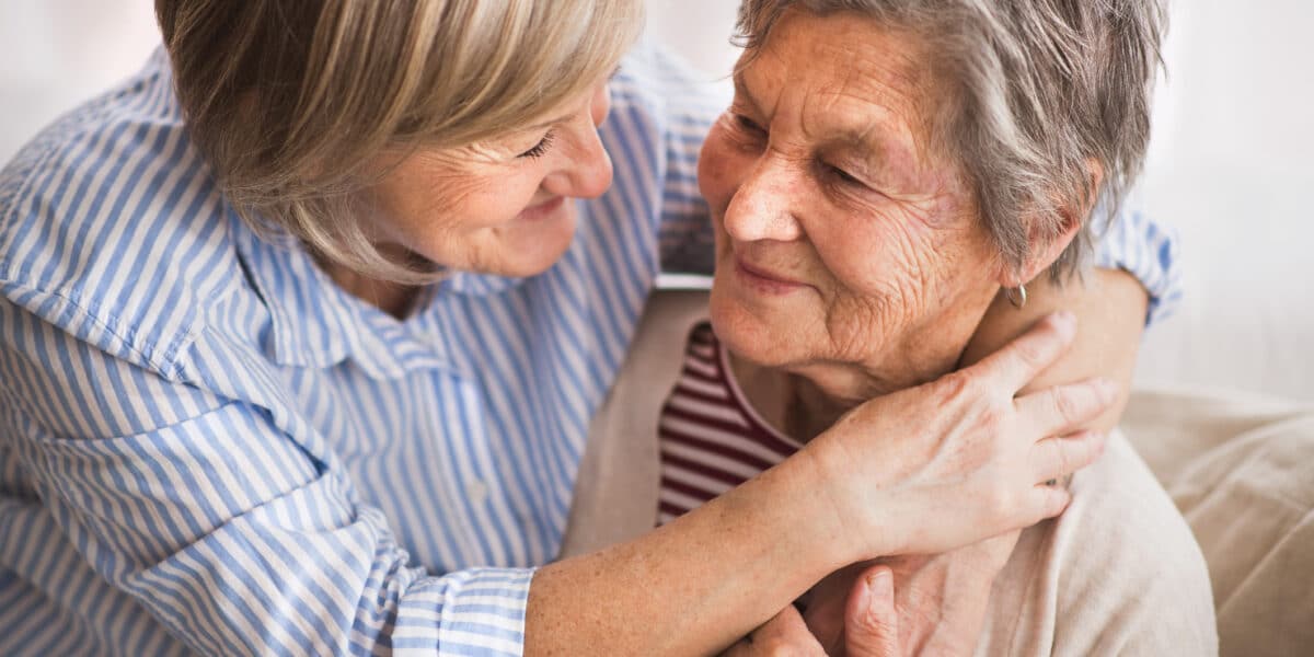 Two senior women at home, hugging. Family and generations concept.