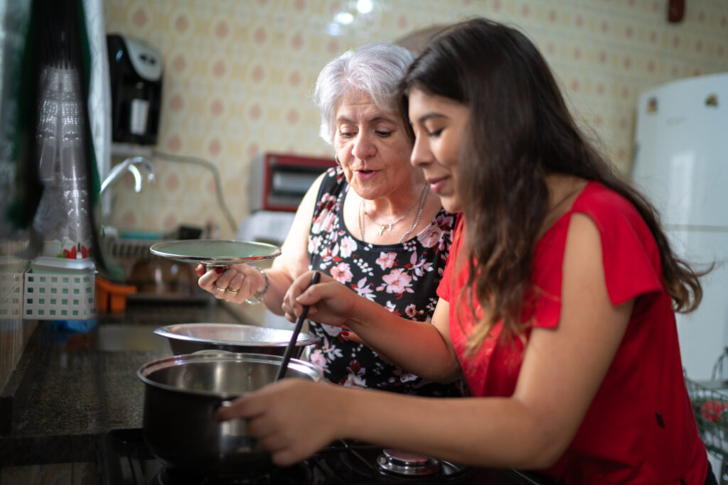 Elderly woman cooking a meal with her daughter at home