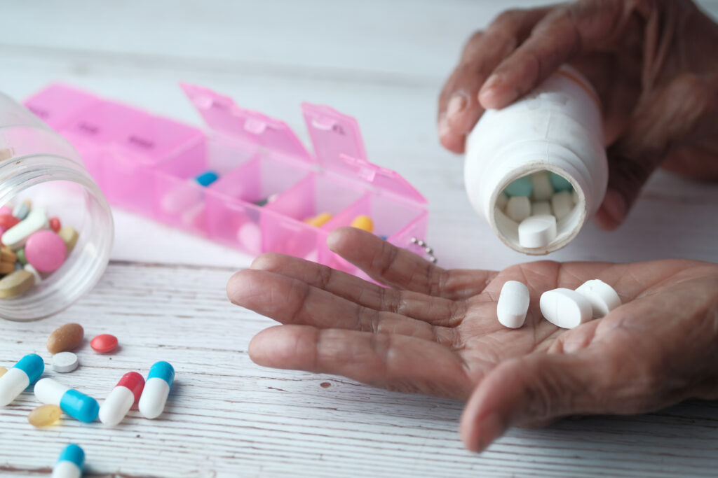 Elderly woman pouring pills from bottle on hand, closeup view