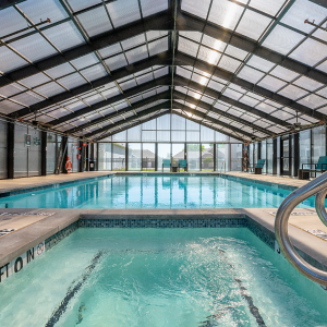 Indoor pool with a hot tub. Glass covering over the pool.
