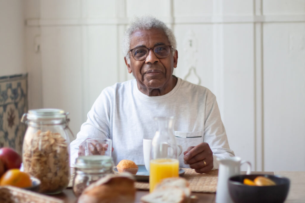 Portrait of aged man resting before breakfast in kitchen.