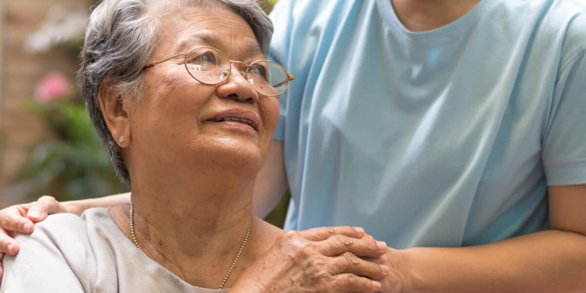 Caregiver, carer hand holding elder hand woman in hospice care.