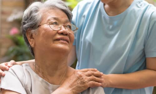 Caregiver, carer hand holding elder hand woman in hospice care.