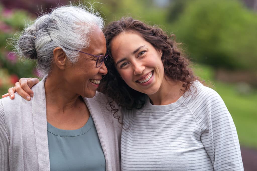 A senior woman embraces her millennial daughter