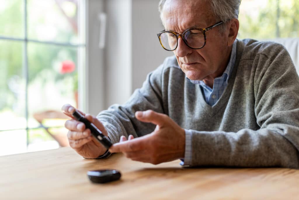 Mature Man Checking Blood Sugar Level With Glucometer