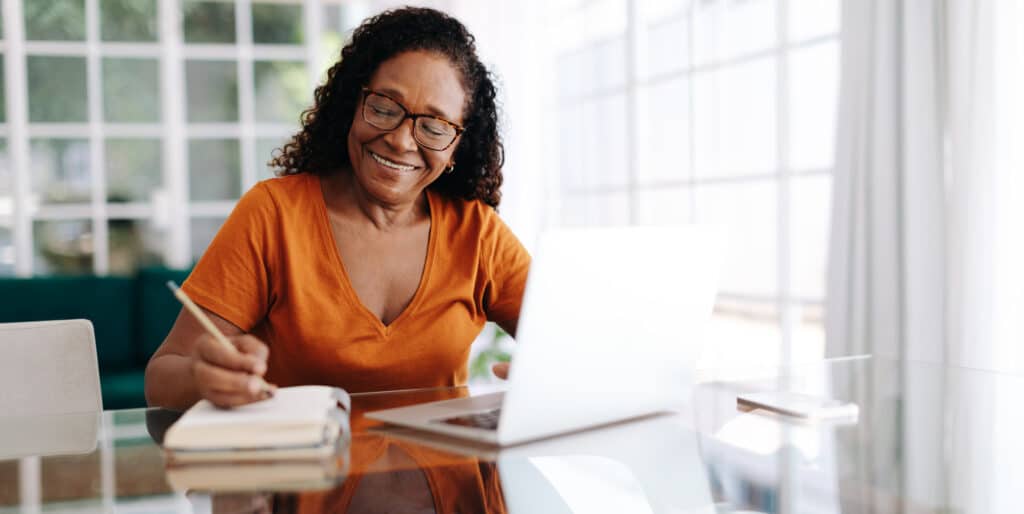 Happy senior woman sitting at a table in her home office