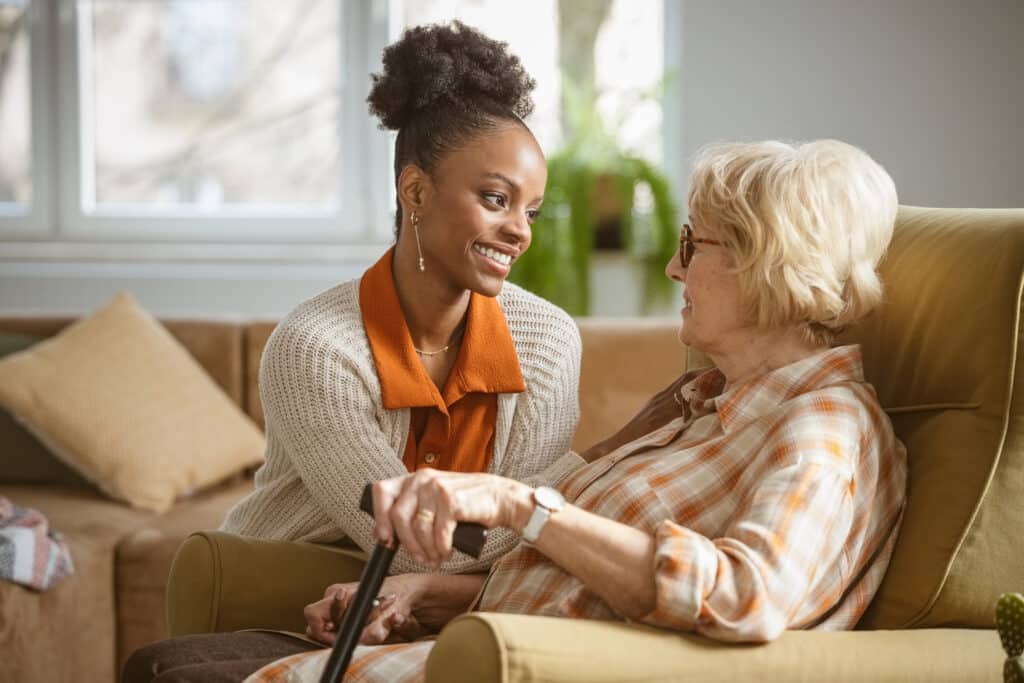 Smiling female home caregiver supporting senior woman in her house