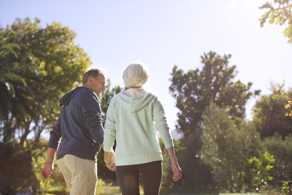 Senior couple holding hands and walking in park

