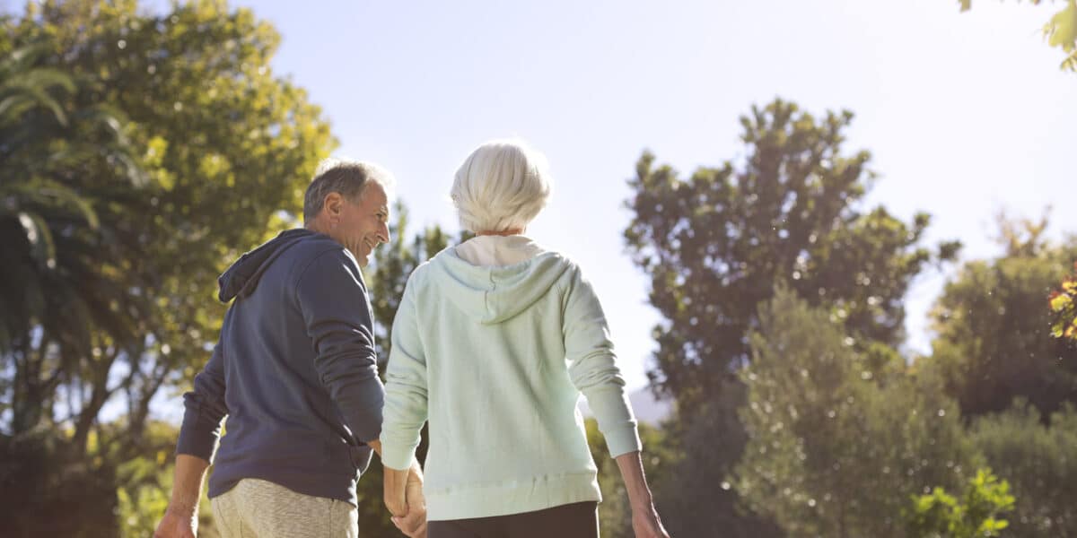 Senior couple holding hands and walking in park