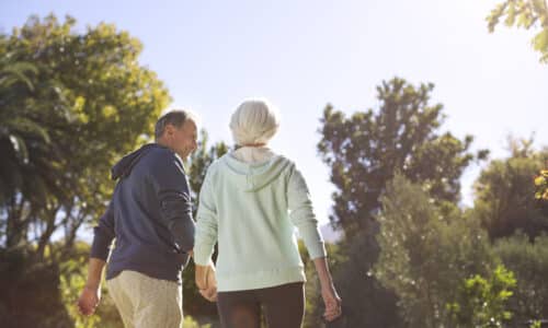 Senior couple holding hands and walking in park