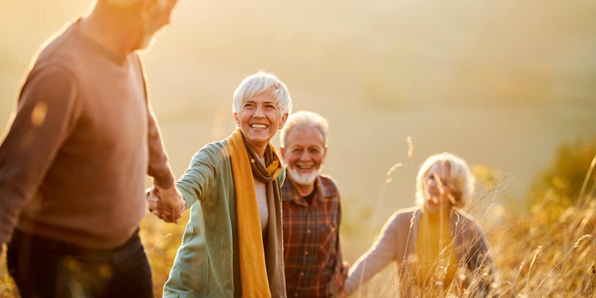 Group of happy mature friends communicating while holding hands and walking