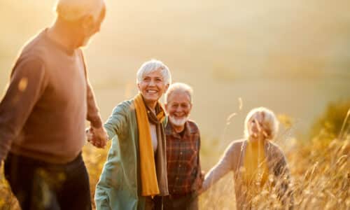 Group of happy mature friends communicating while holding hands and walking