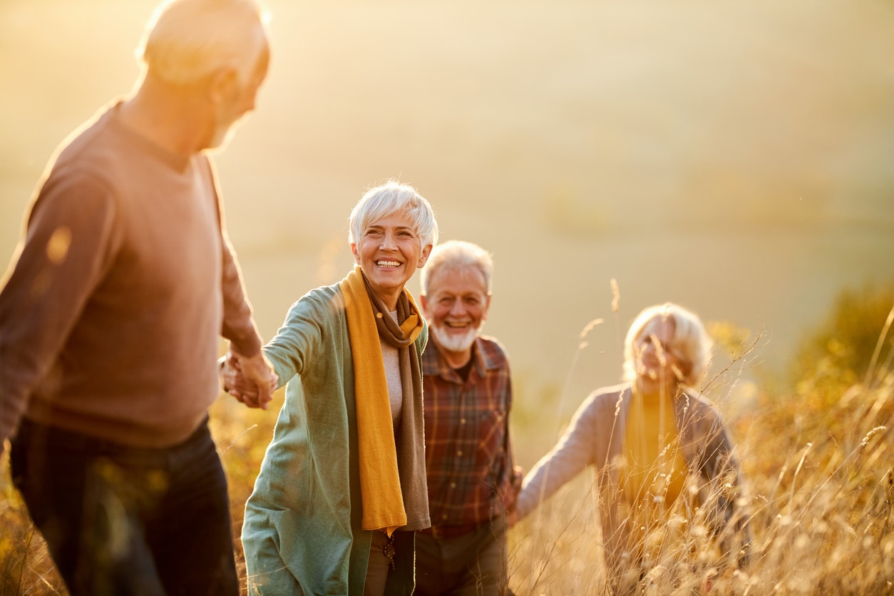 Group of happy mature friends communicating while holding hands and walking