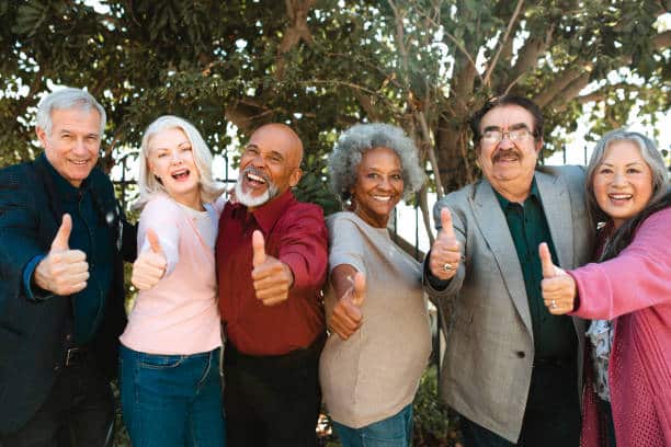 Cheerful retired senior friends all doing thumbs up.